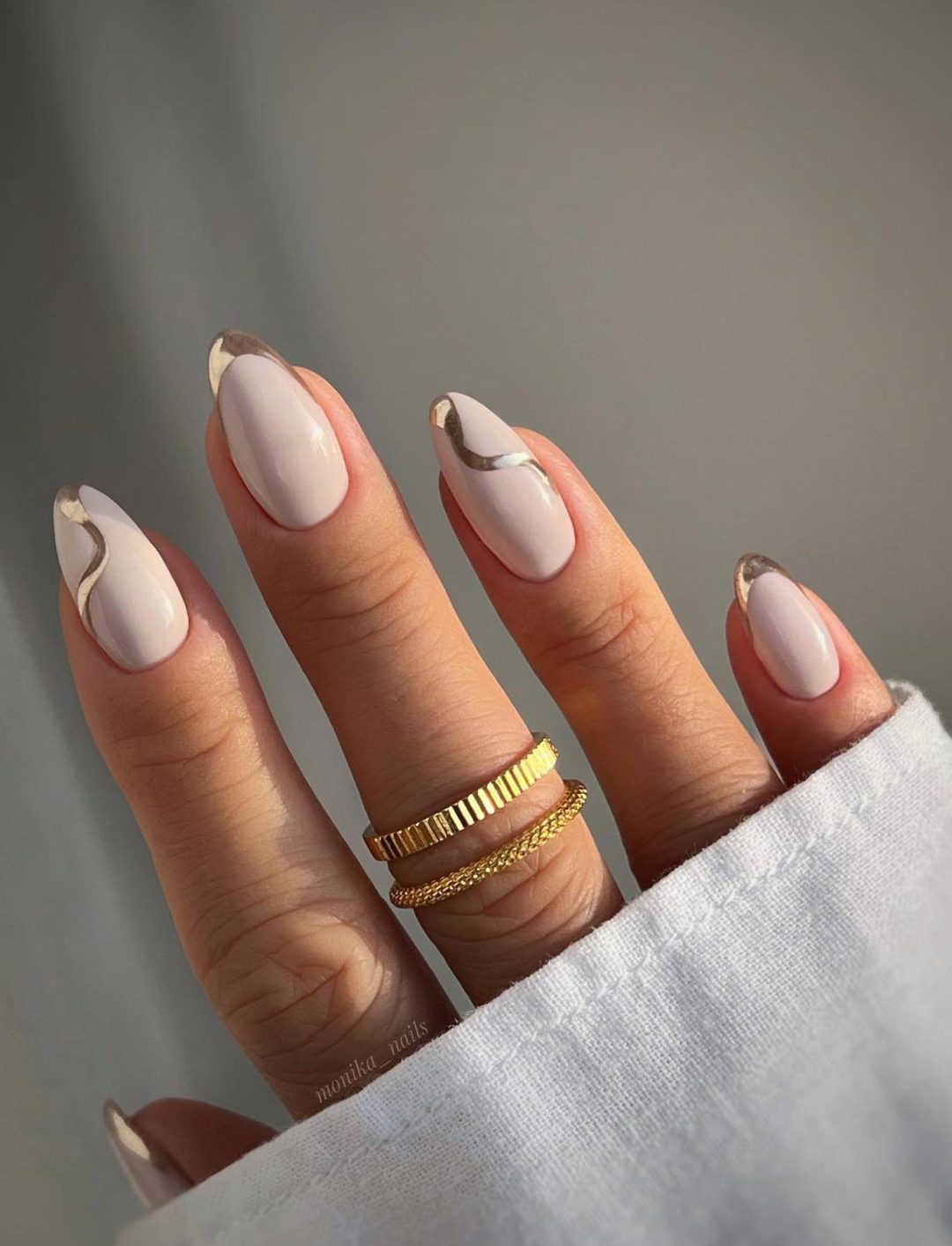 Abstract white nails with gold swirls.