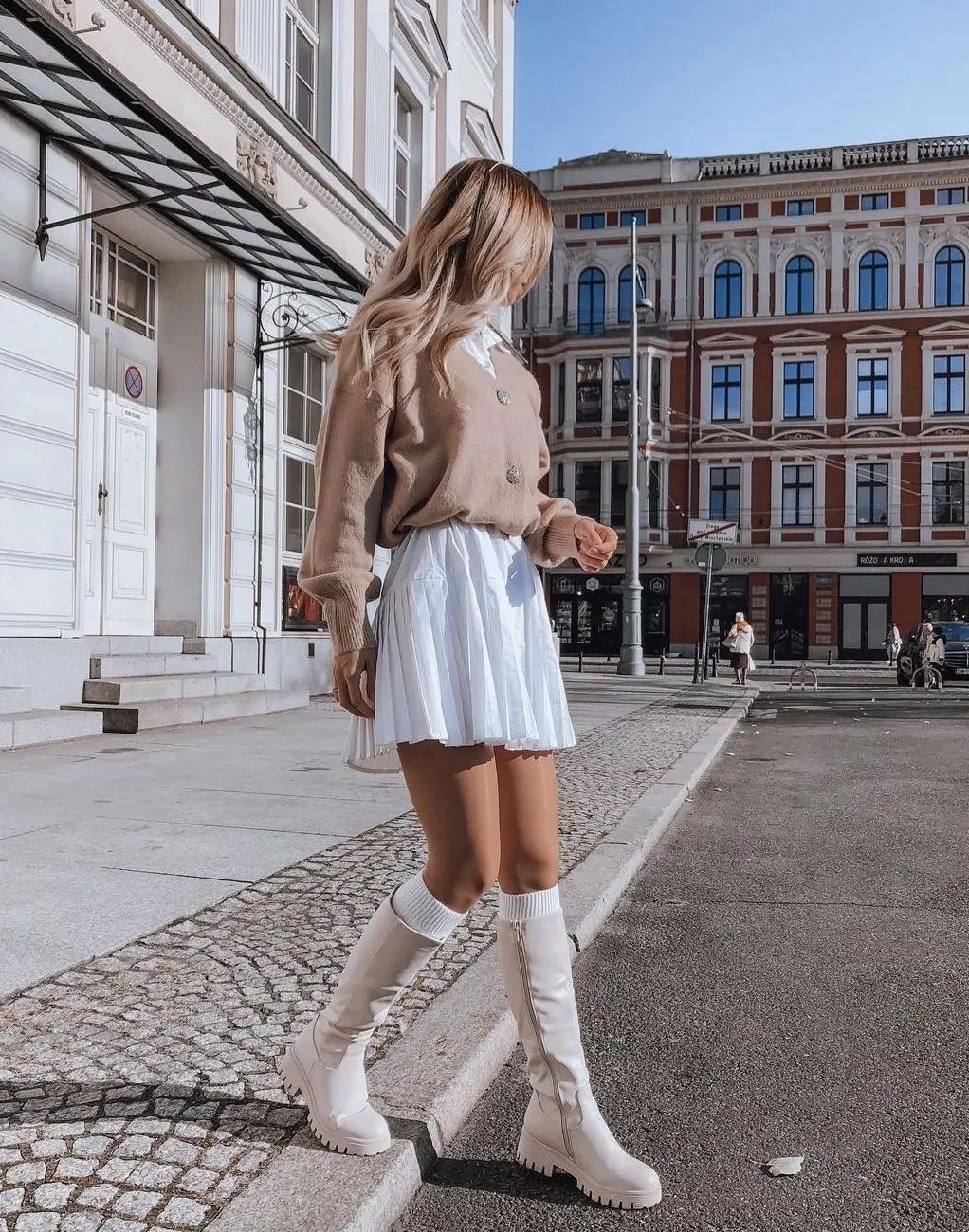 Chic preppy outfit with white skirt and beige boots.