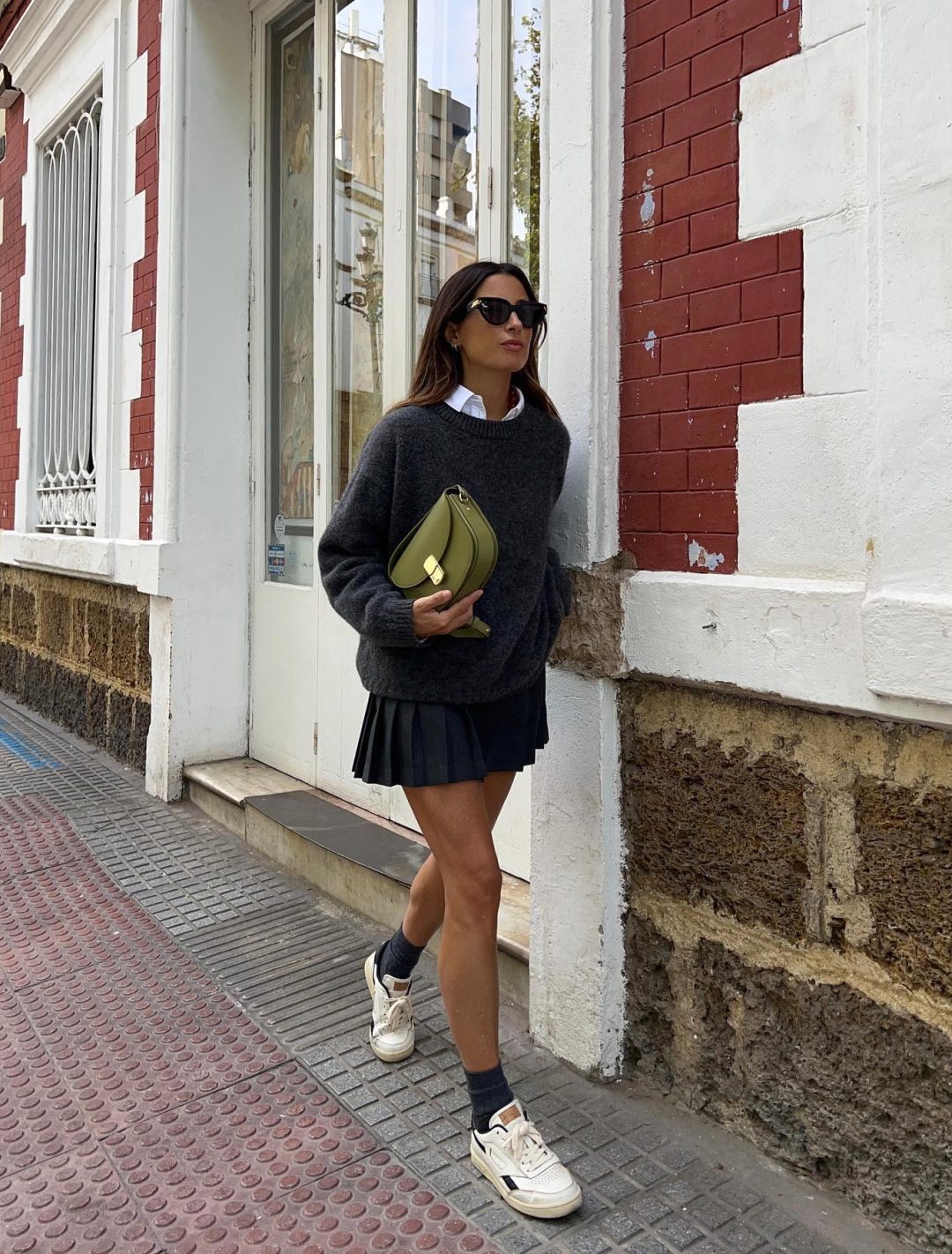 Preppy tennis skirt outfit with a grey sweater and collared shirt.