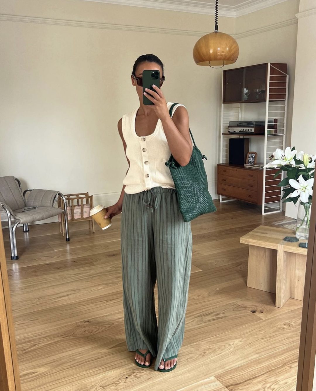 Girl wearing a white sleeveless top with green pants and a green woven handbag