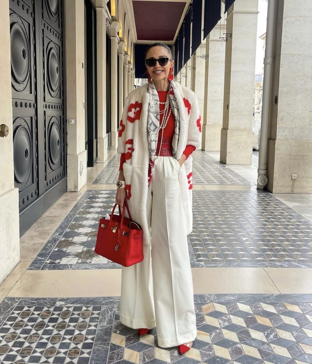 Girl wearing a red fitted top with white palazzo pants and a red Hermès birkin bag