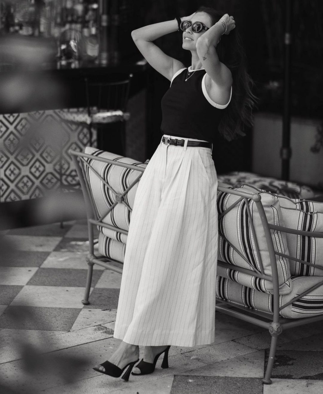 Girl wearing a black tank top with striped palazzo pants and black mules