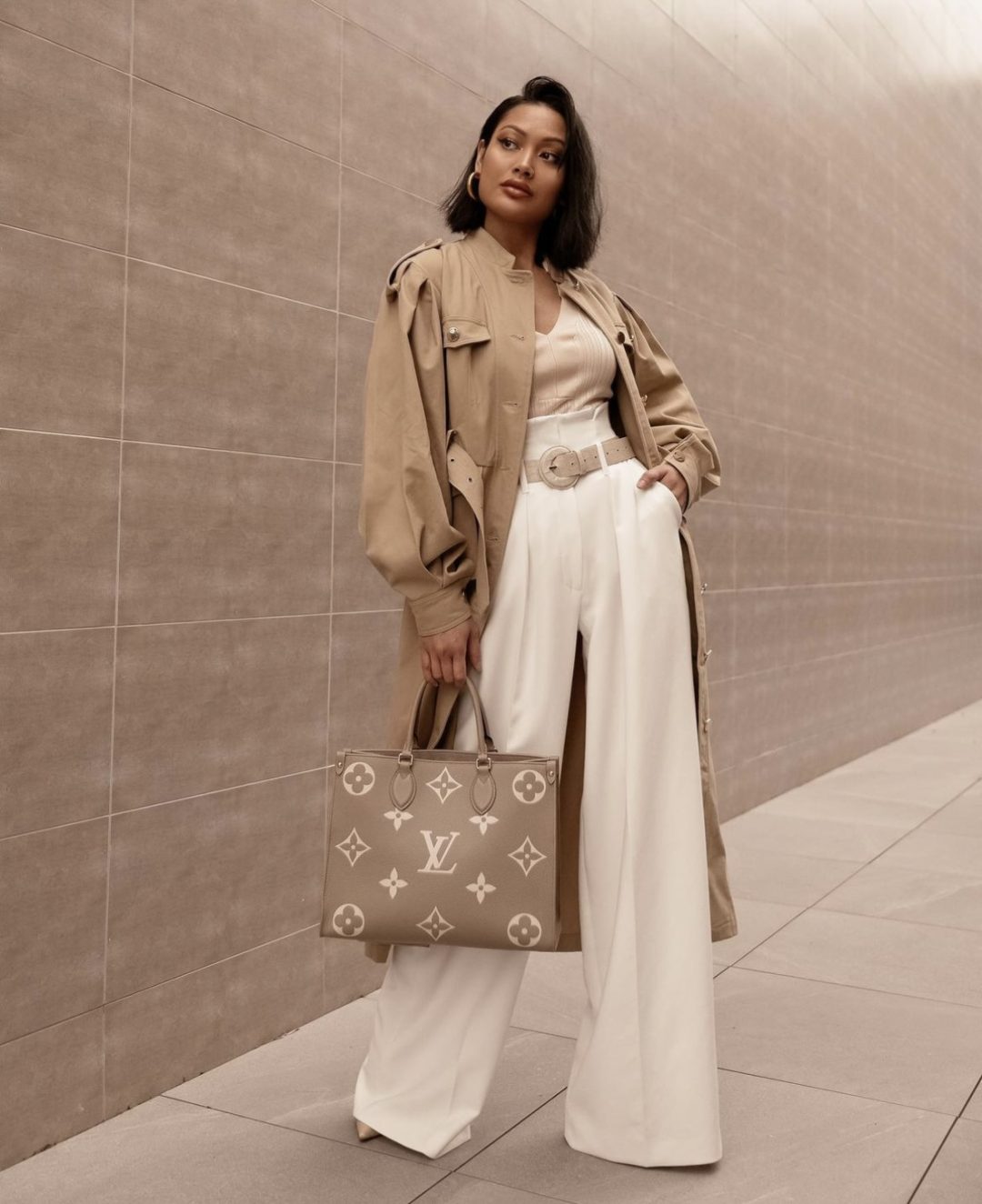 Girl wearing a beige bodysuit with white high-waisted palazzo pants and a trench coat.