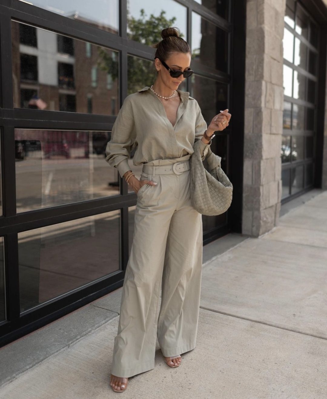 Girl wearing palazzo pants, button up shirt and hobo bag in a grey monochrome tone.