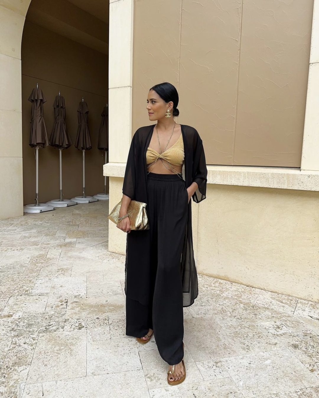 Girl wearing a black kimono and wide leg pants with a statement gold clutch