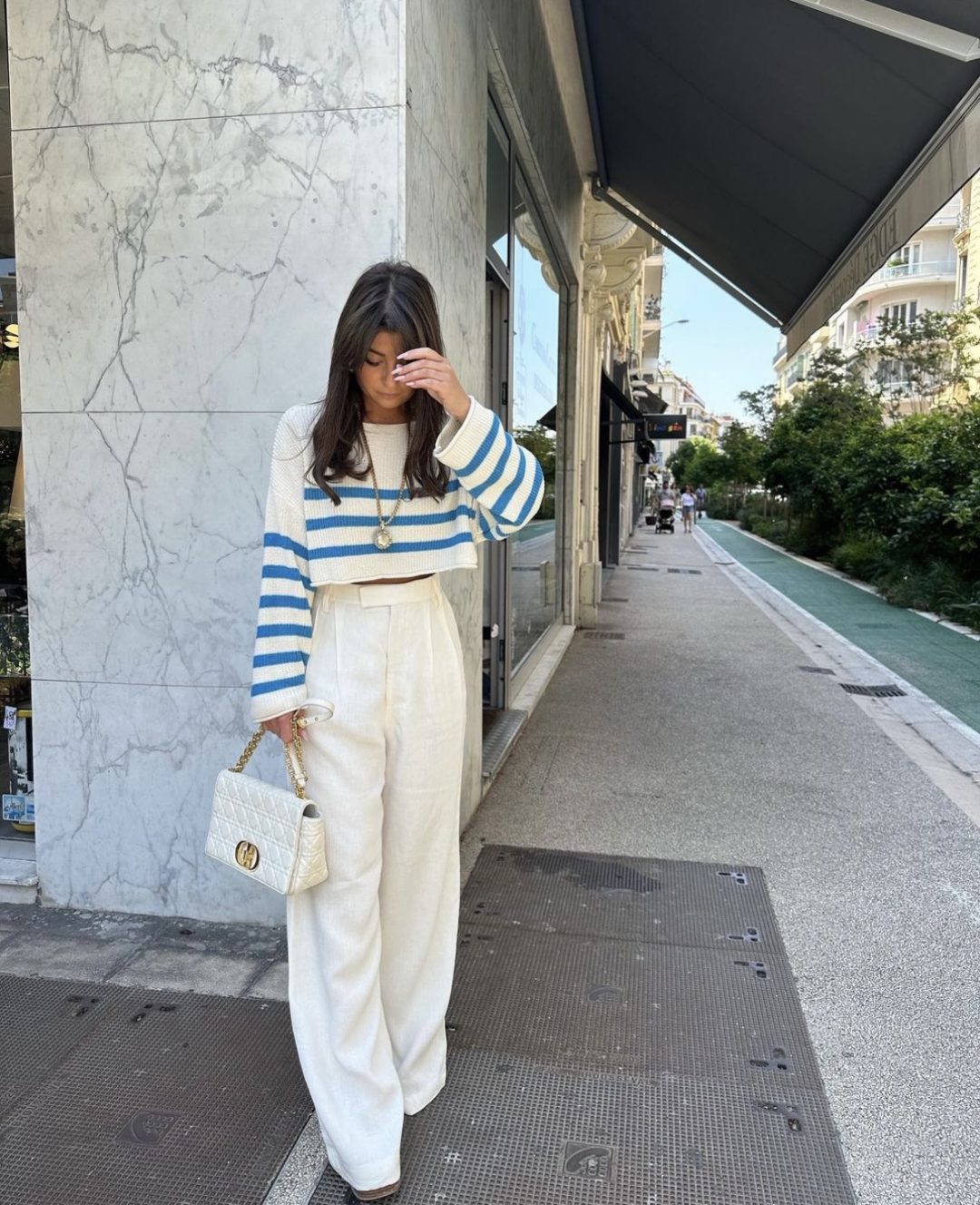 Girl weaing white fitted palazzo pants with a cropped striped sweater and white dior handbag