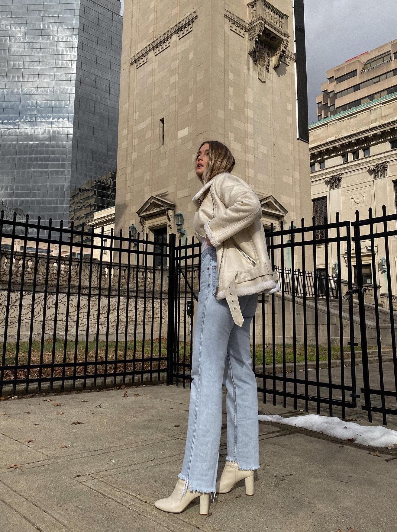 Light wash jeans outfit with white ankle boots and cream aviator jacket.