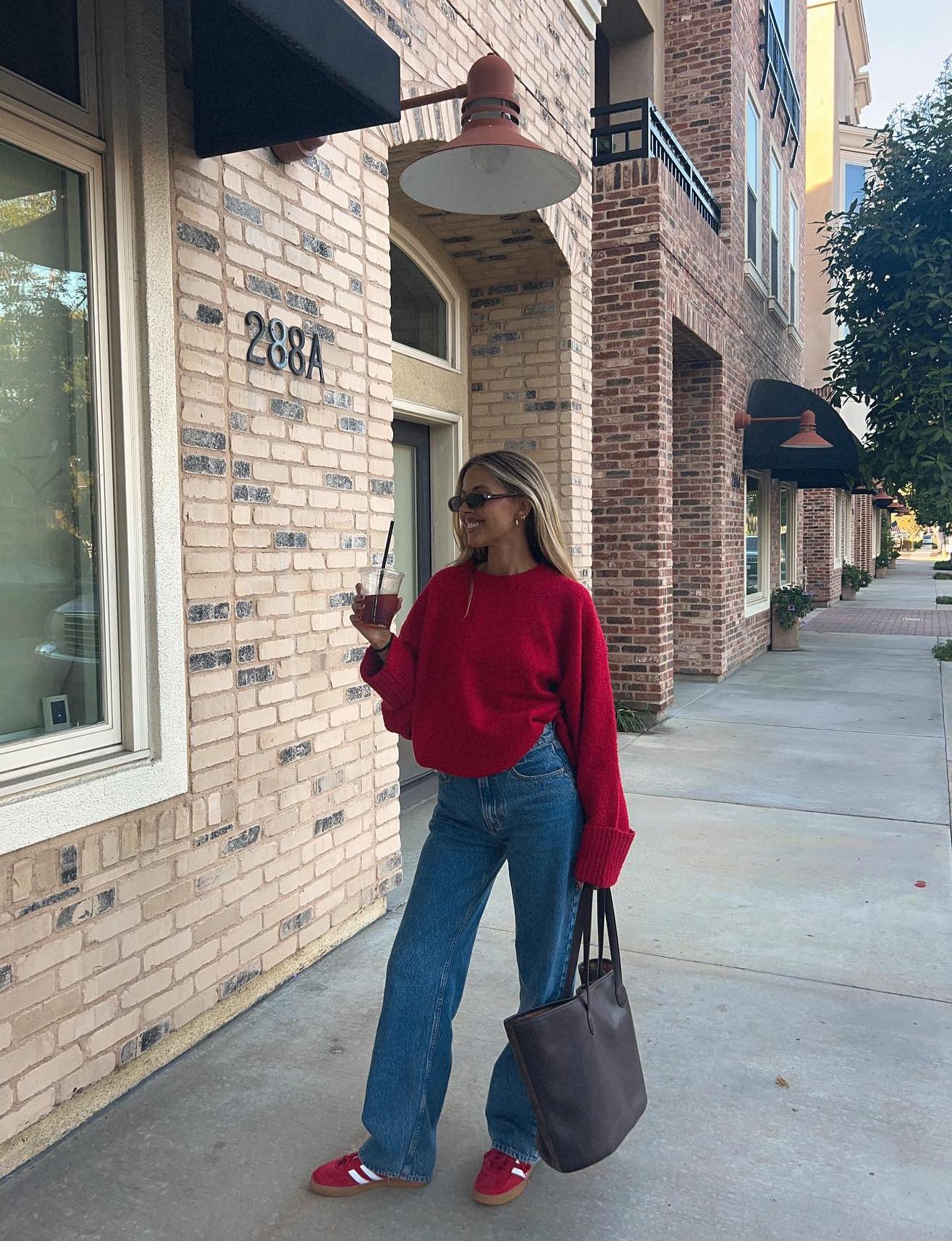 Casual jeans outfit with a red sweater and red Adidas Samba sneakers.