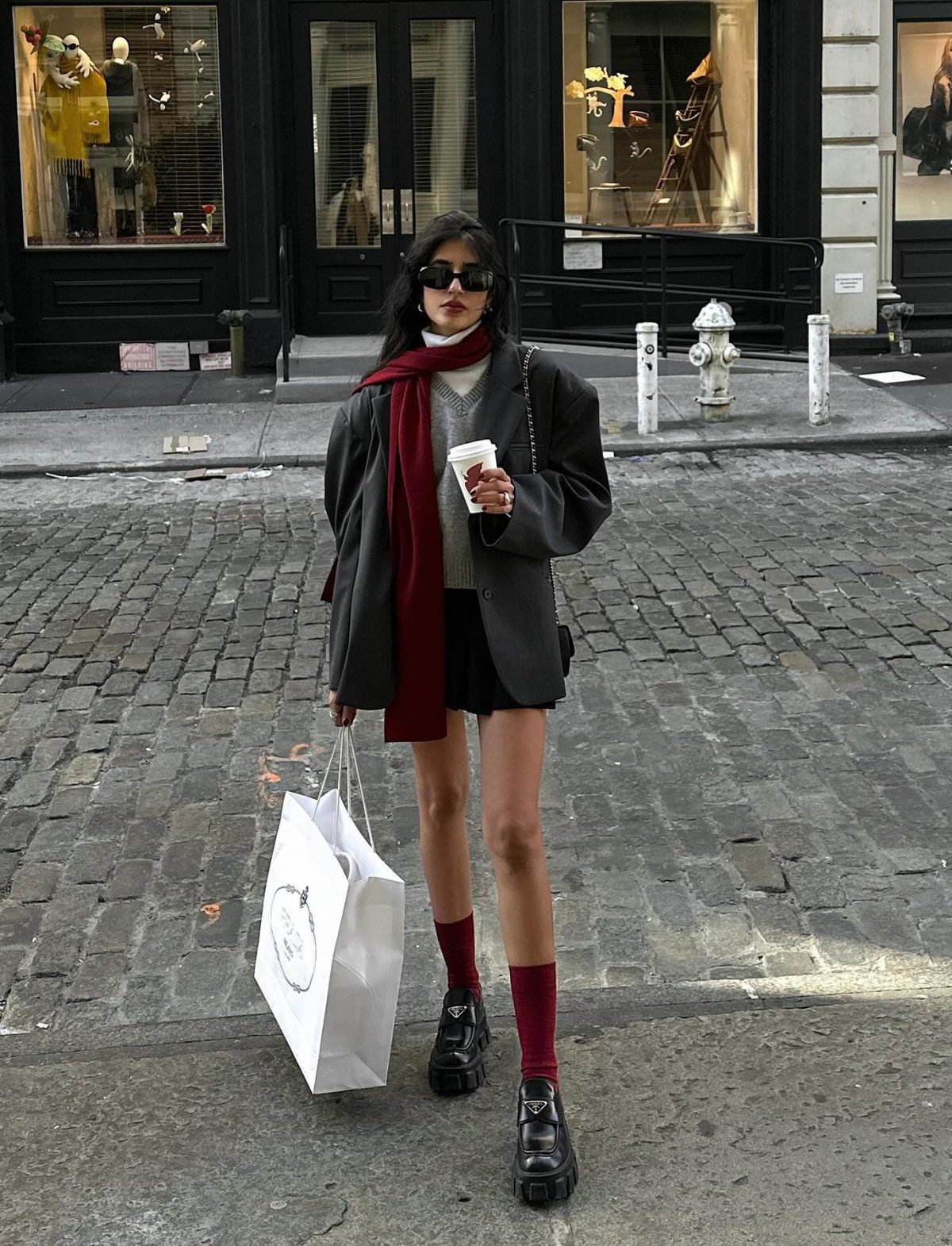 Preppy outfit with a grey blazer, loafers and red details.