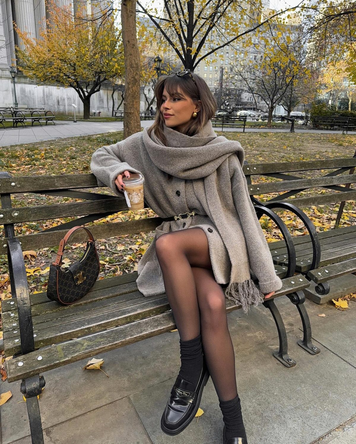 Chic fall outfit with a beige scarf coat and loafers with black socks.