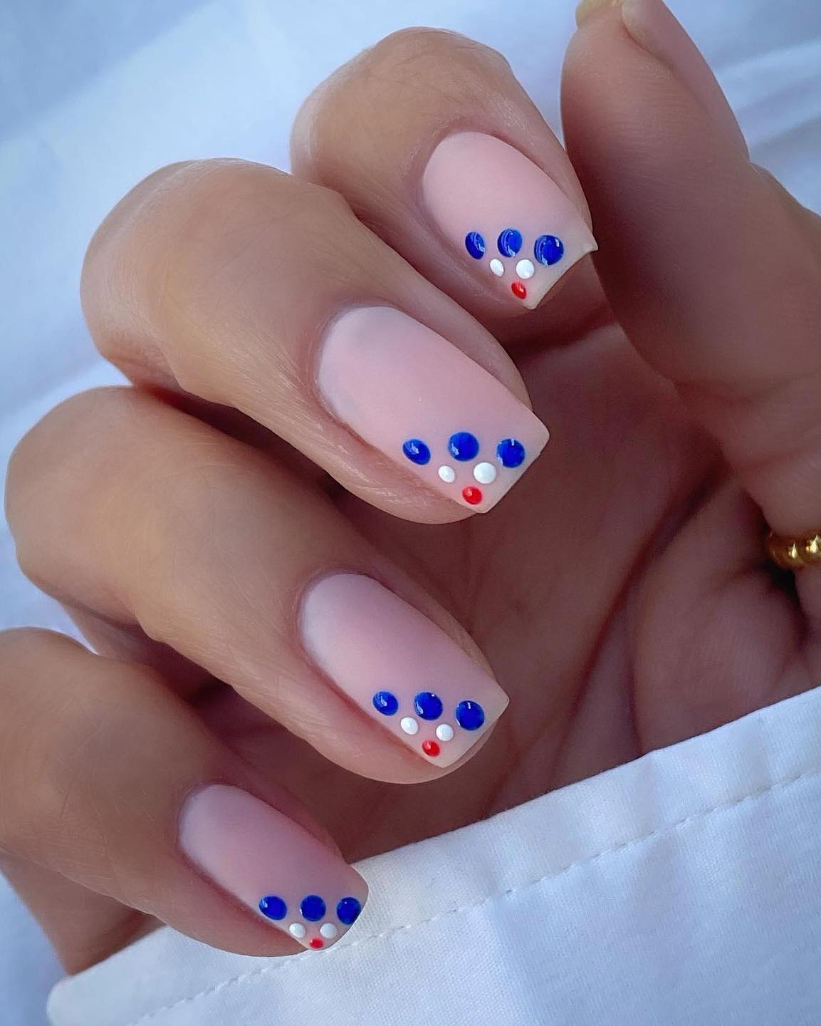 Neutral nails with blue, white and red dots.