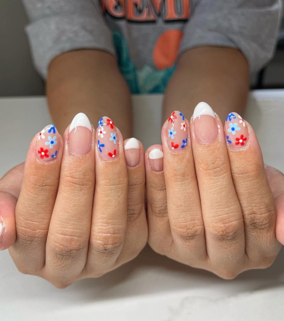 White French tip nails with red and blue daisies.