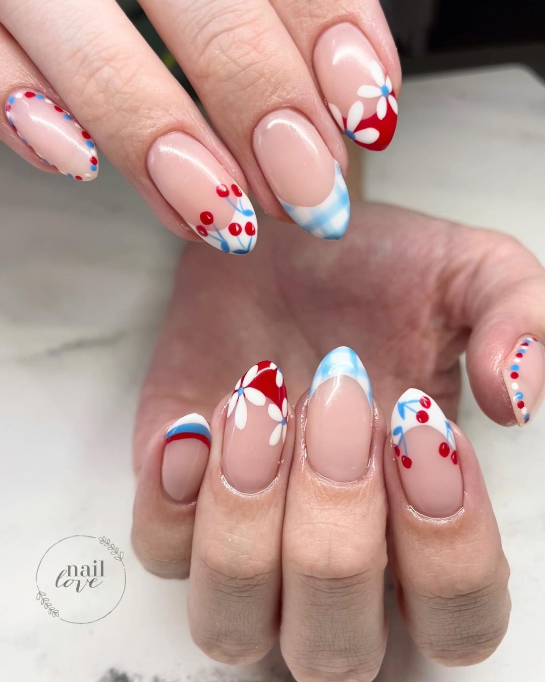 Pale blue and red French tip nails with cherries.