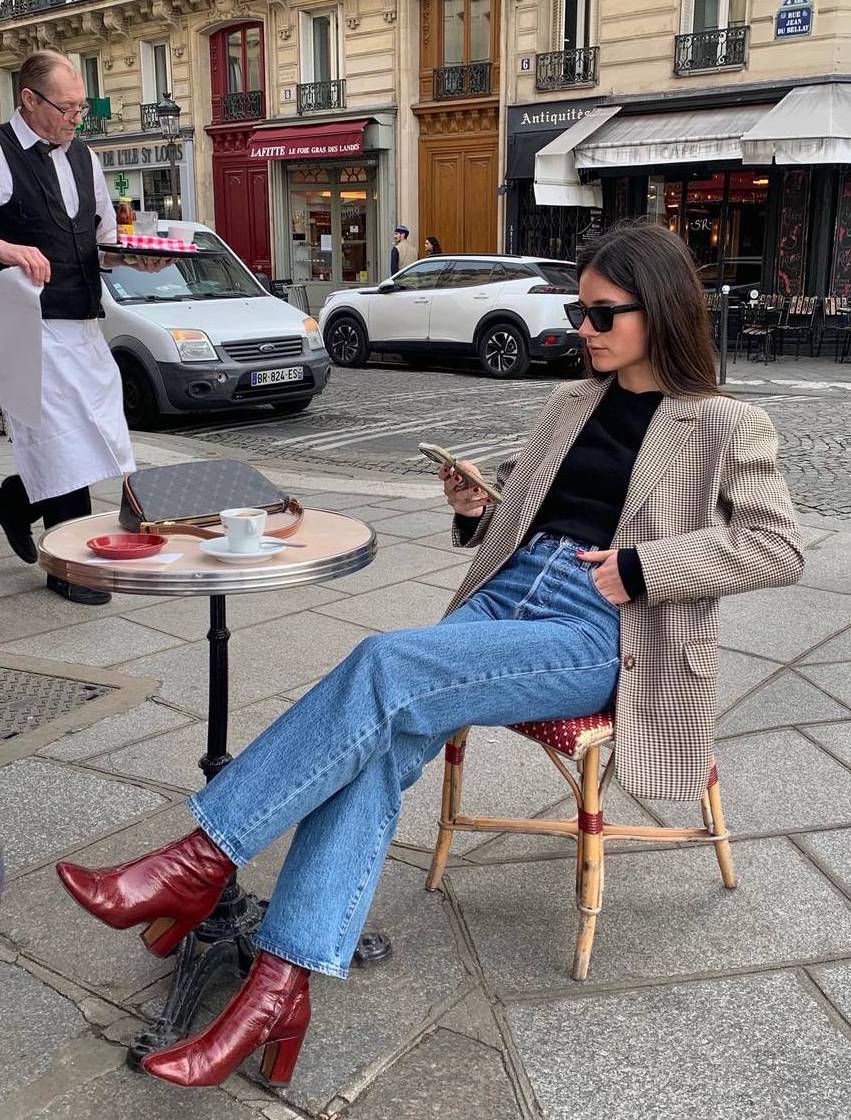 Chic burgundy boots outfit with a checkered blazer and jeans.