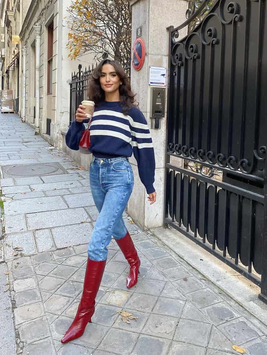 Blue jeans with burgundy boots and a striped blue sweater.