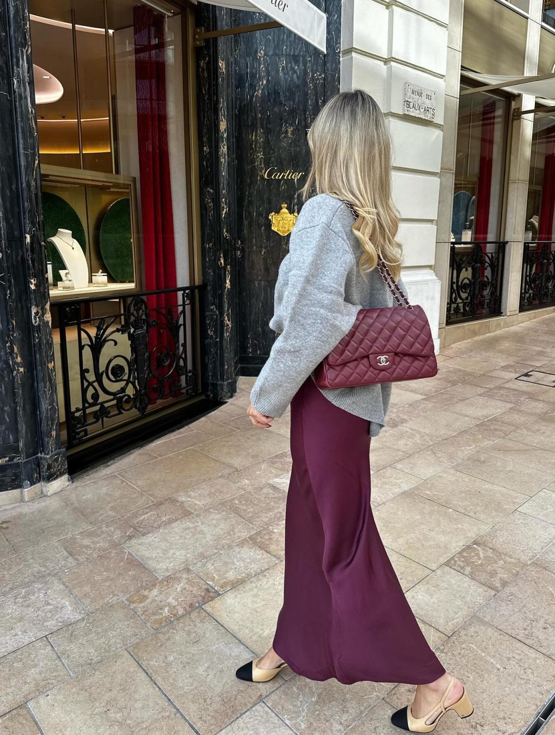 Plum satin skirt outfit with grey sweater and burgundy Chanel bag.