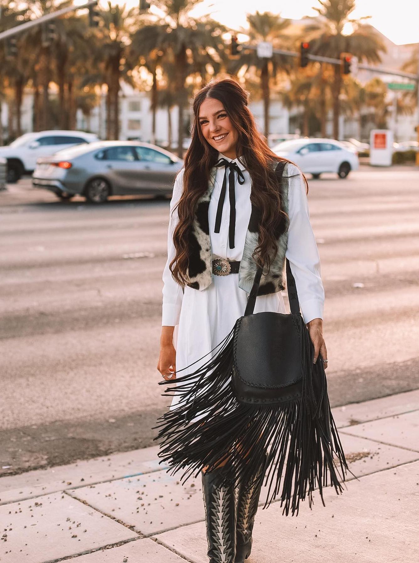 Chic rodeo outfit with a black fringe bag and black cowboy boots.