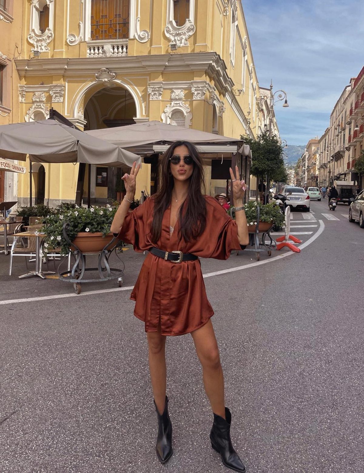 Chic Western outfit with a burnt orange dress and short black cowboy boots.