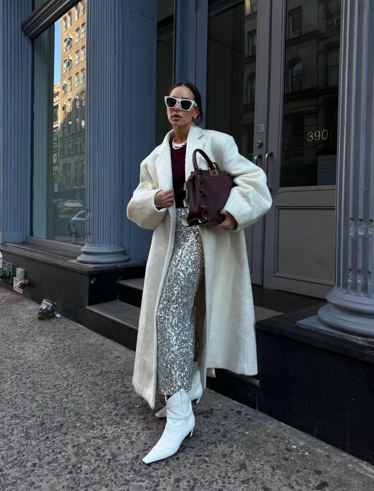 Long silver sequin skirt outfit with a white coat and short white cowboy boots.