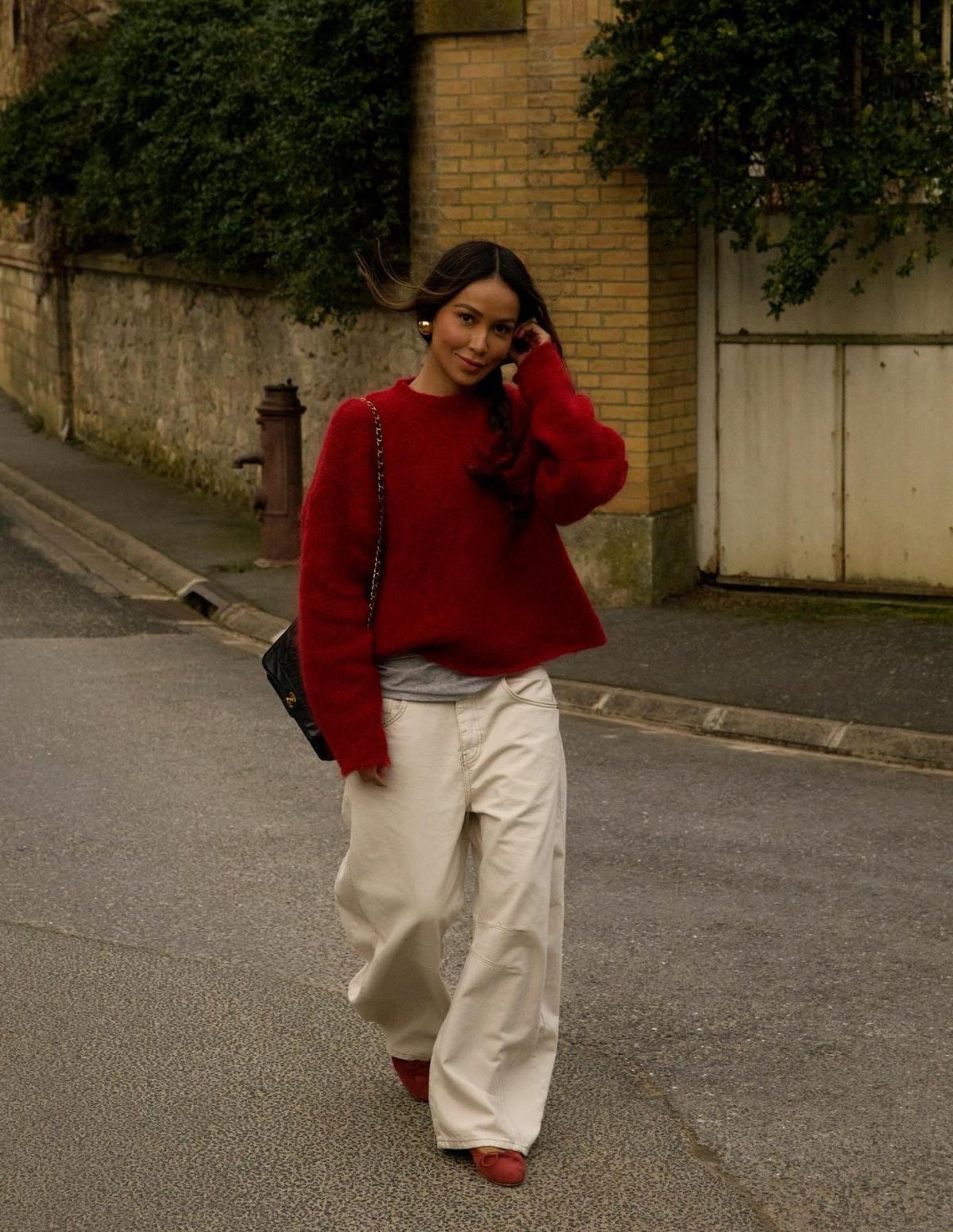 Chic outfit with a red sweater and ballet flats with white baggy jeans.