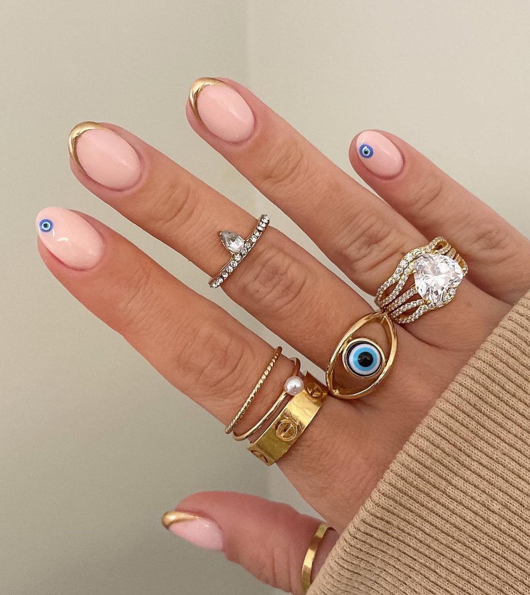 Cute short nails with evil eye nail art an gold French tips.