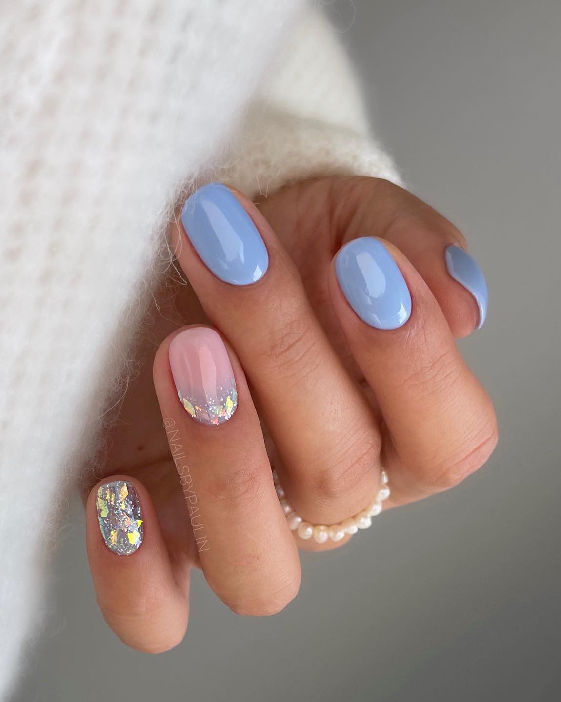 Unhas curtas azul bebê com glitter prateado.