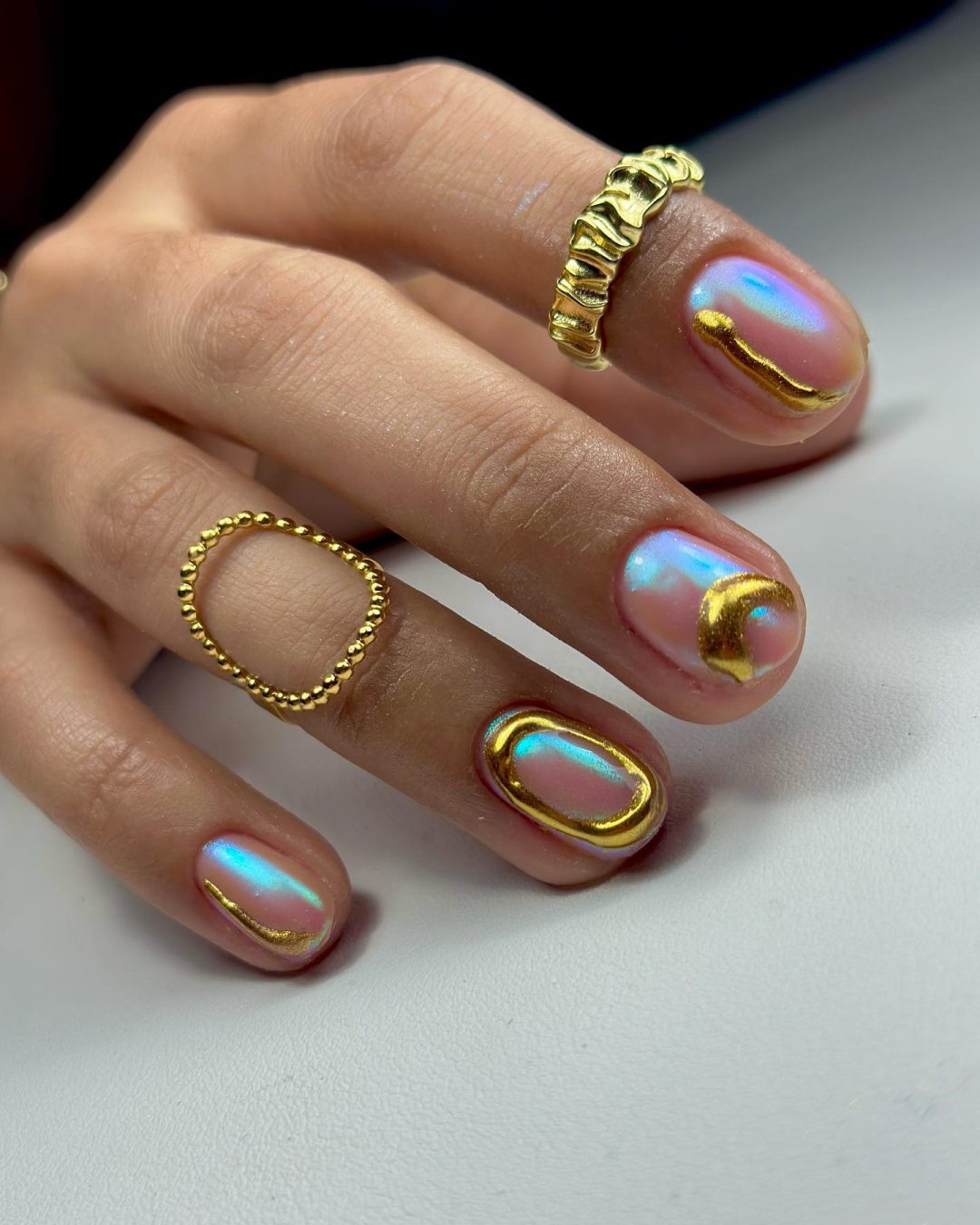 Short holographic nails with gold details.