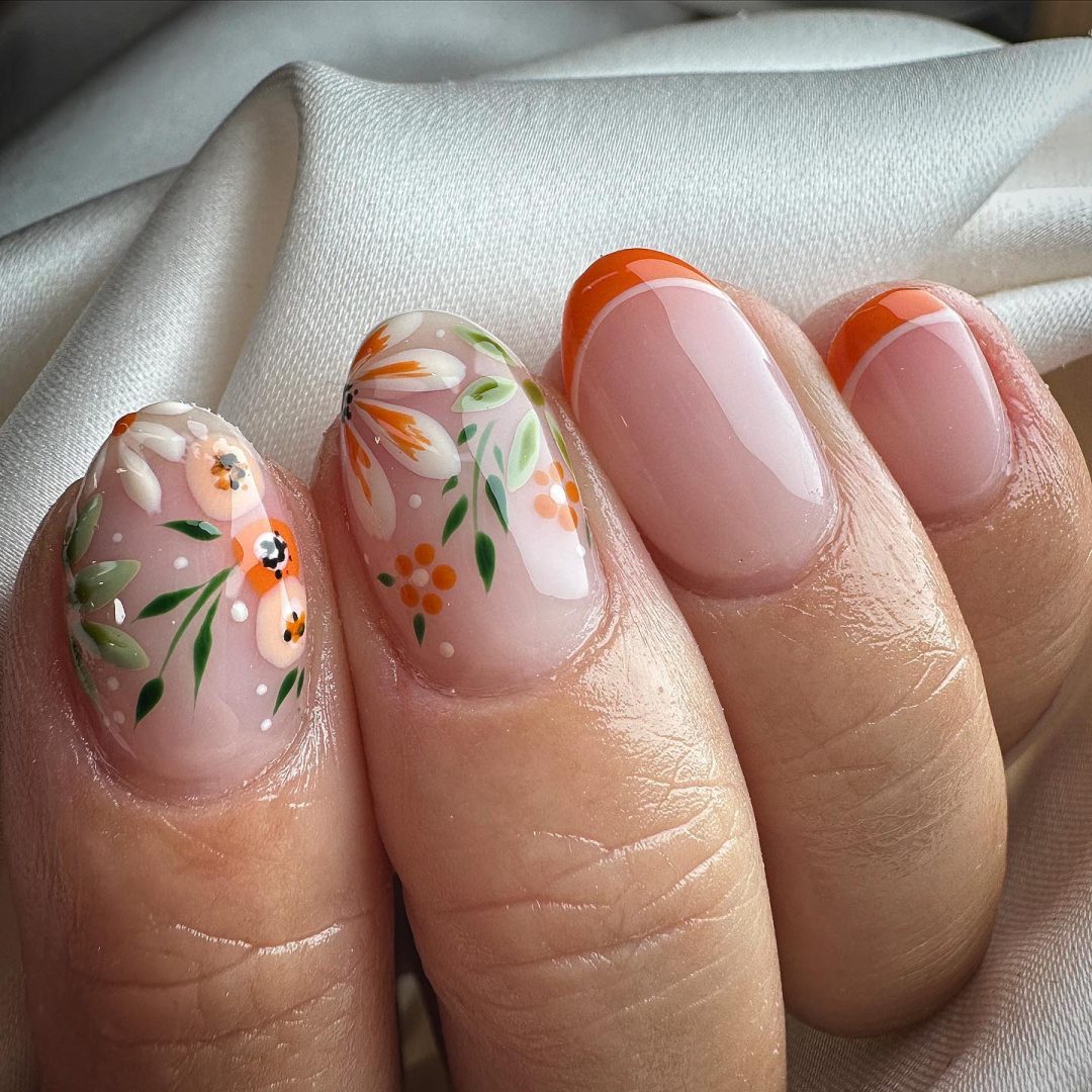 Uñas cortas de color naranja quemado con flores y puntas francesas.