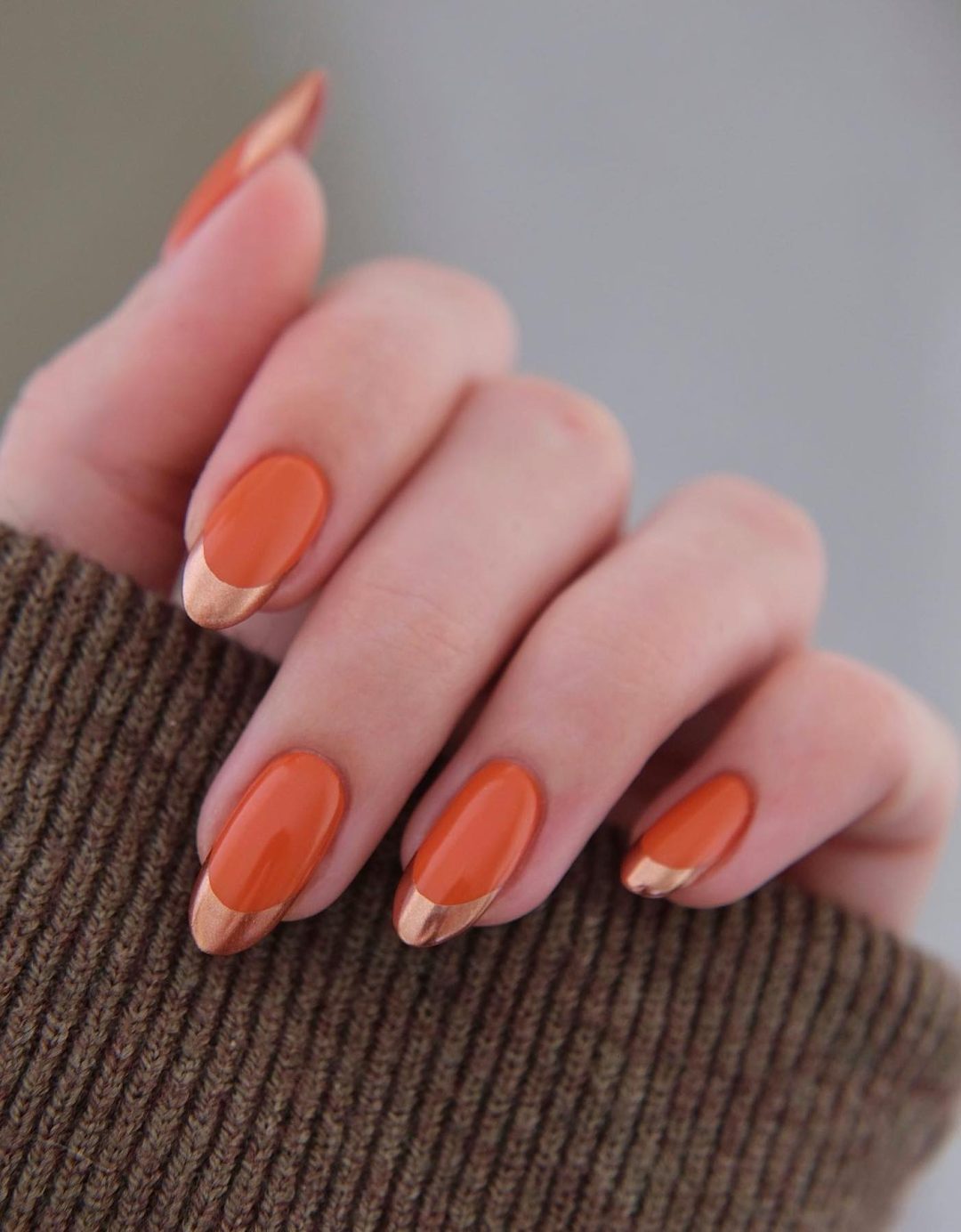 Uñas color naranja quemado con puntas francesas cromadas.