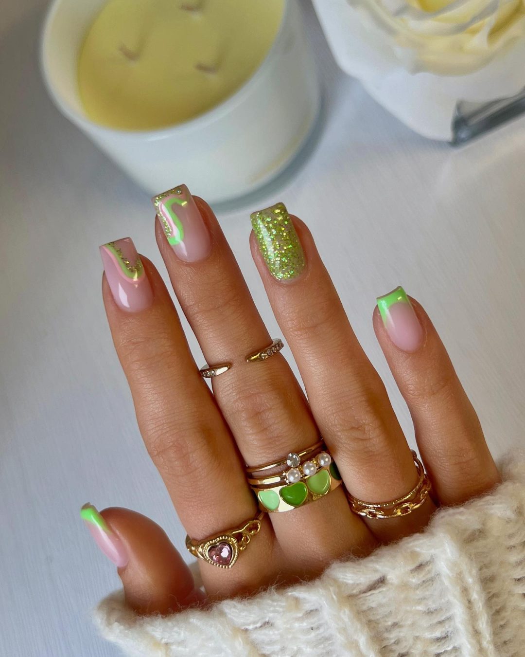 Short light green nails with French tips and glitter.