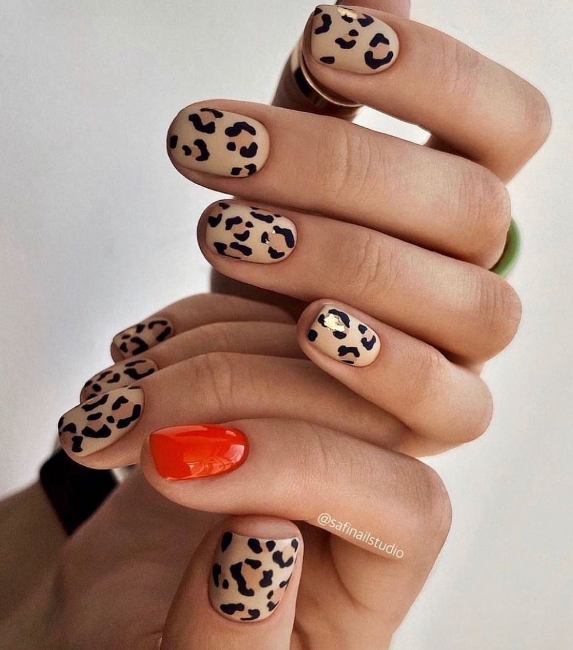 Unhas curtas com estampa de leopardo e laranja brilhante.