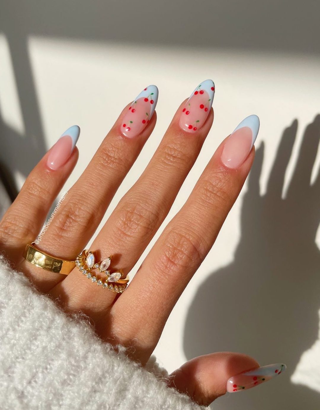Pale blue French tip nails with cherry art.