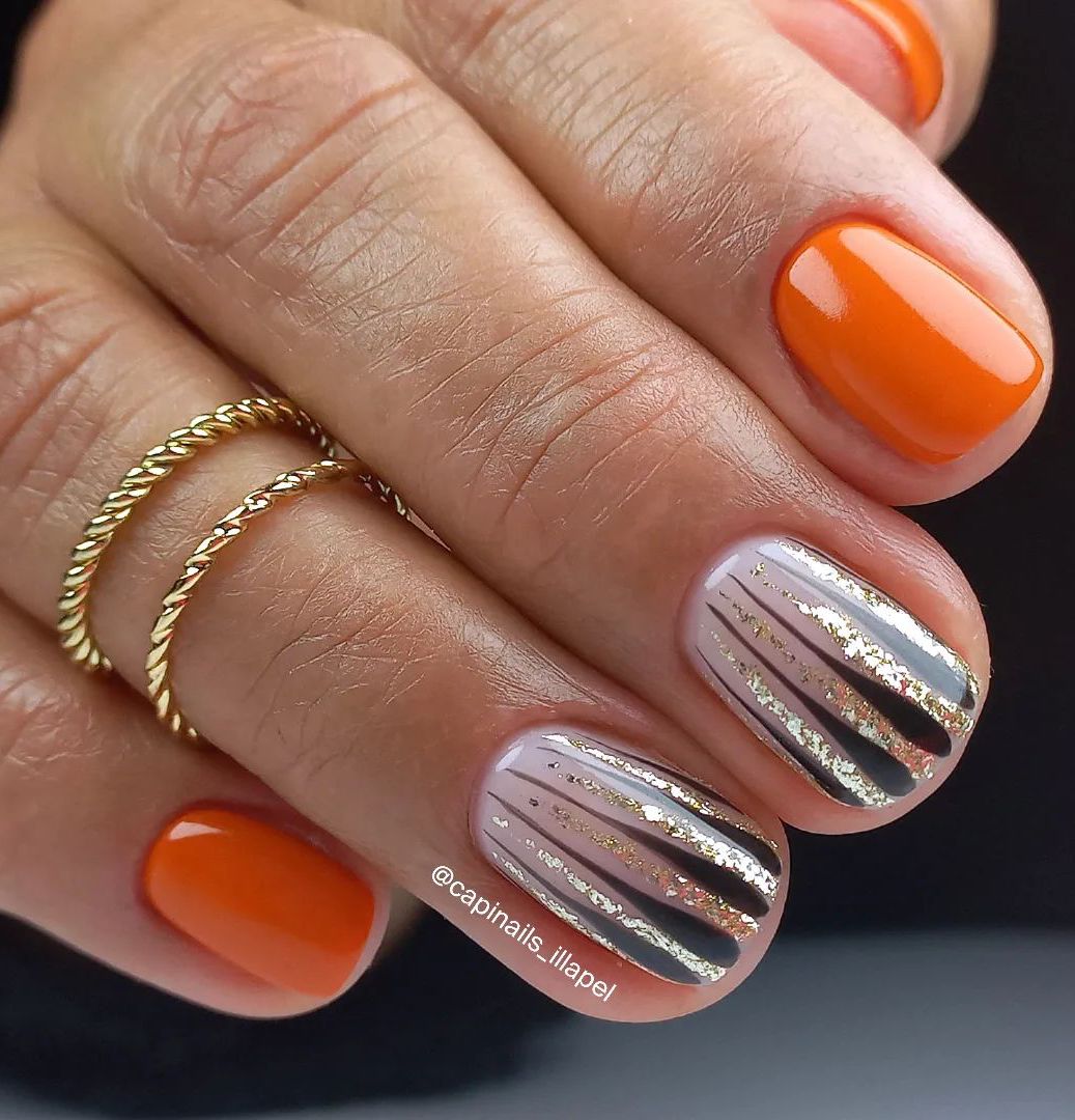 Uñas cortas de color naranja quemado con rayas negras y doradas.