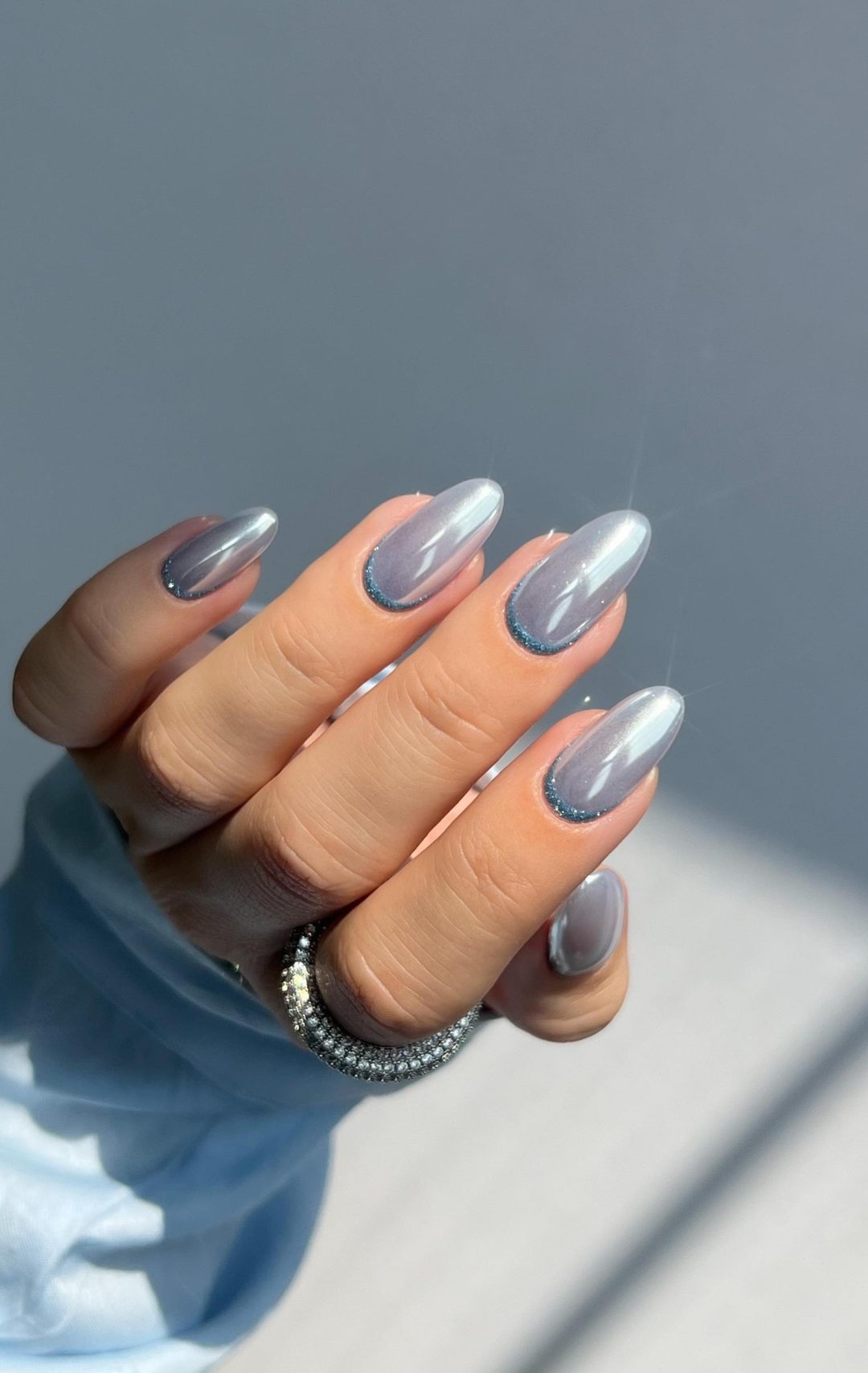 Holographic silver nails with blue glitter.