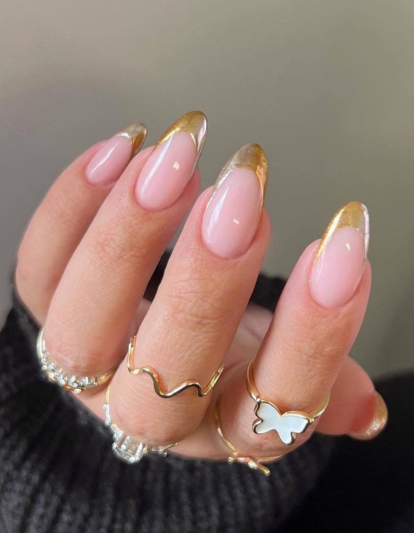 Glossy gold French tip nails in almond shape.