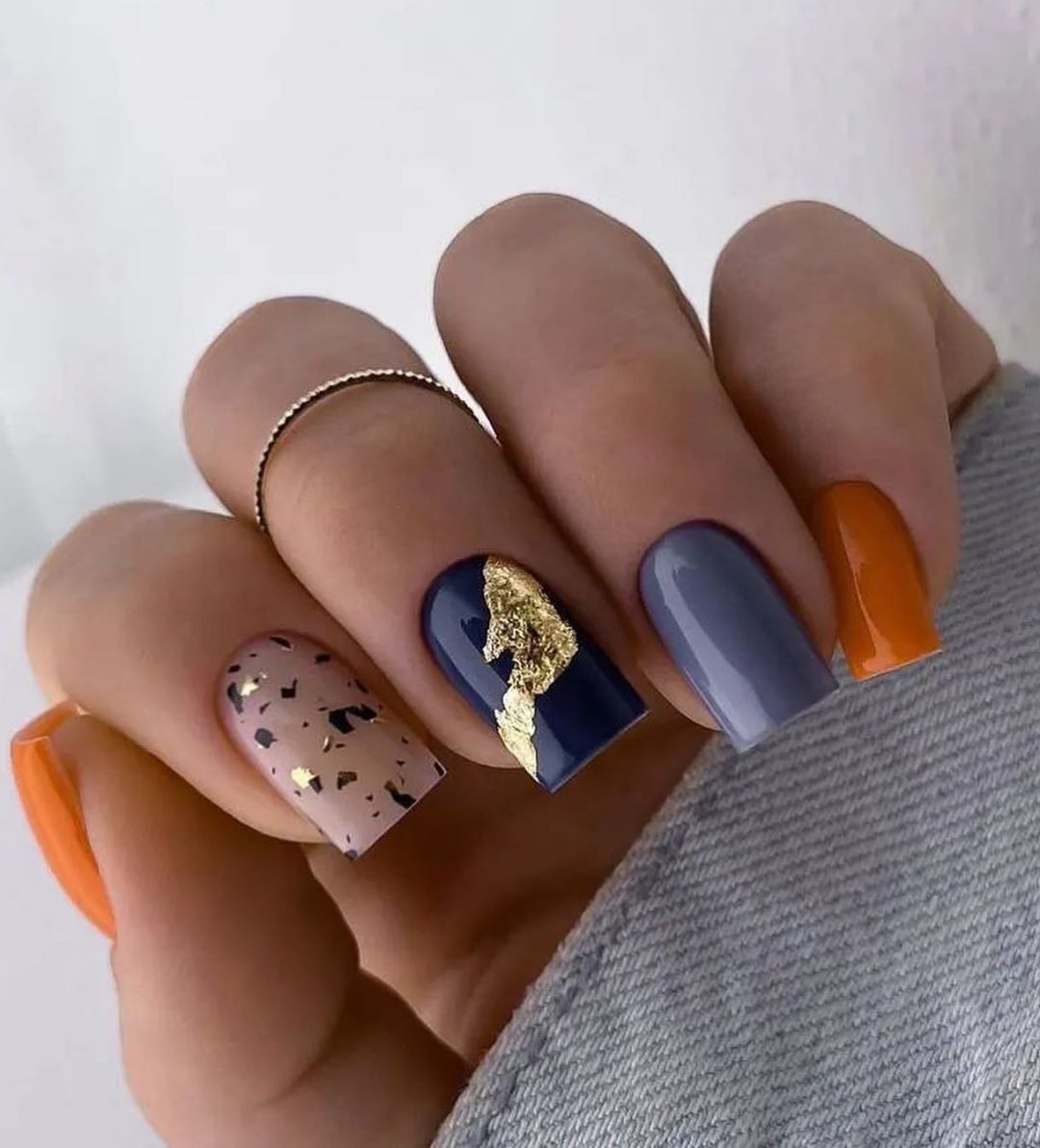 Uñas de otoño en tonos naranja quemado y azul marino.