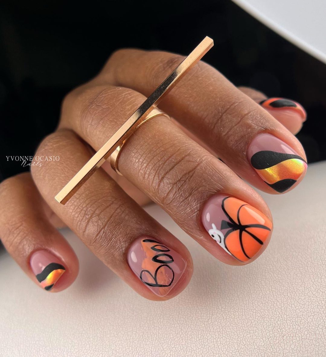 Short orange Halloween nails with pumpkins.