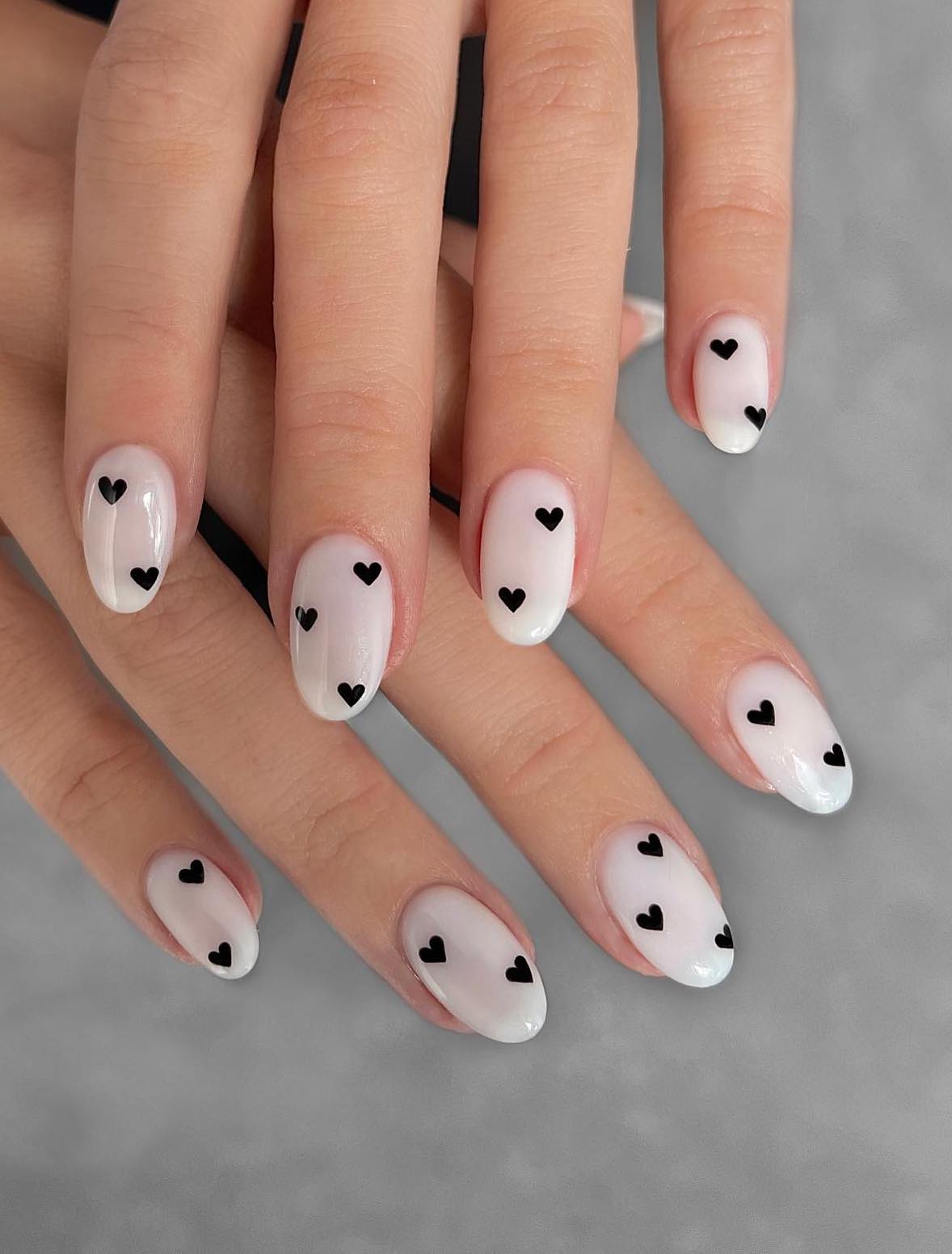 Milky white nails with black hearts.