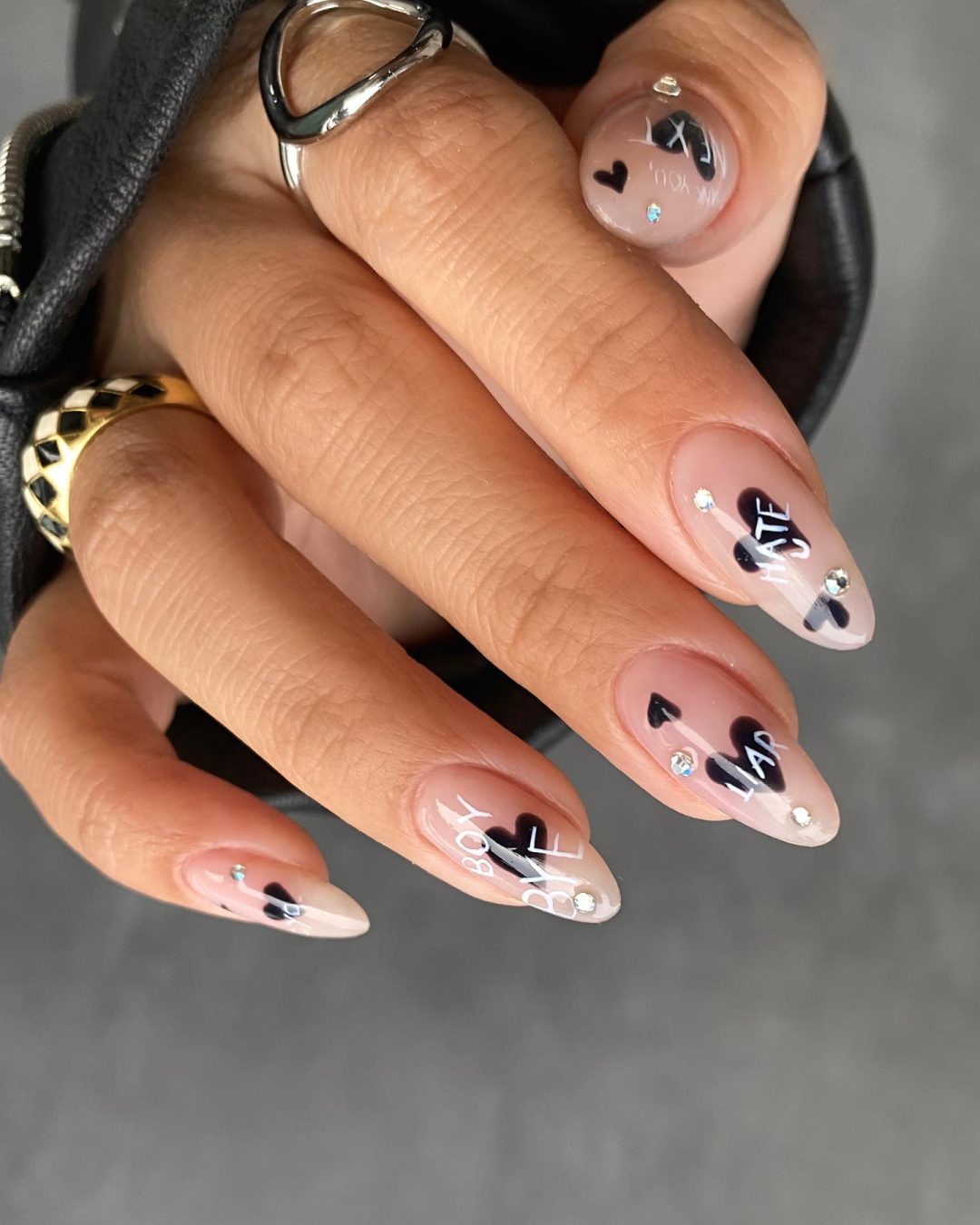 Neutral Valentine's day nails with black hearts and crystals.