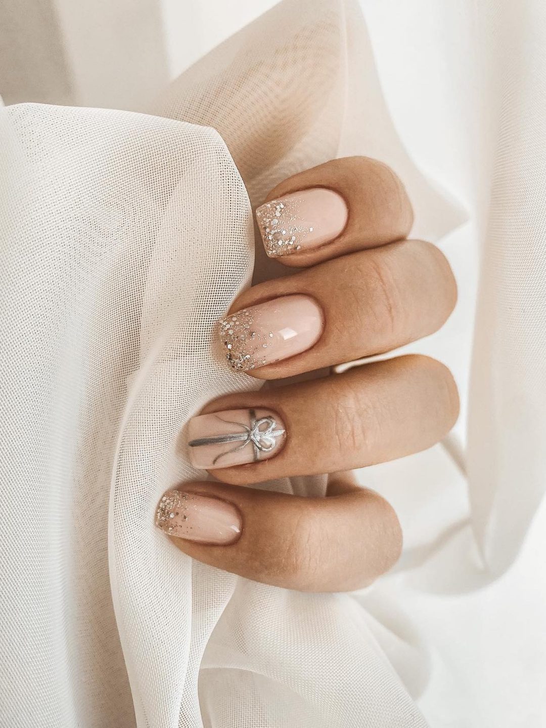 Neutral Christmas nails with gold glitter.