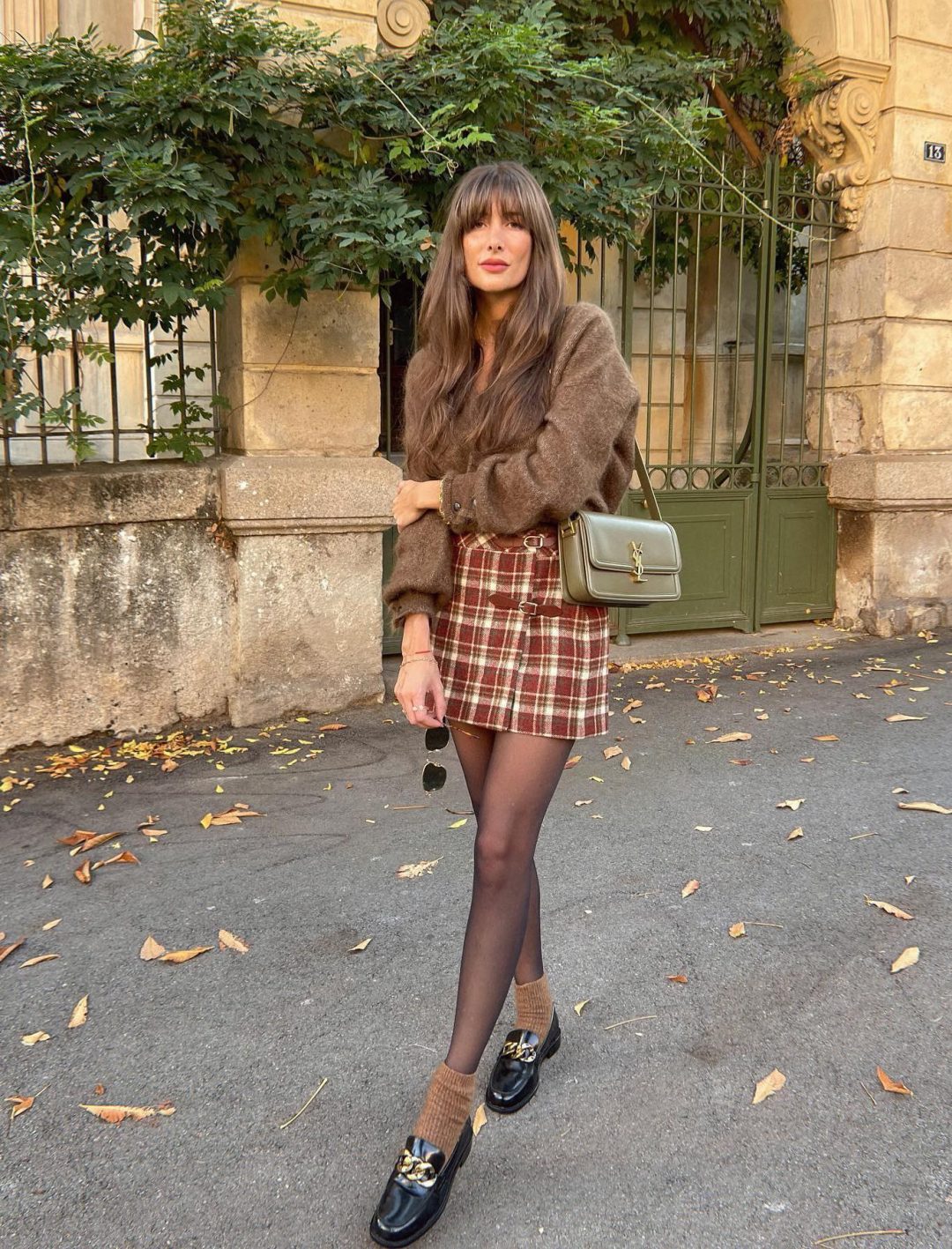 Classy dark academia outfit with mini plaid skirt and brown cardigan.
