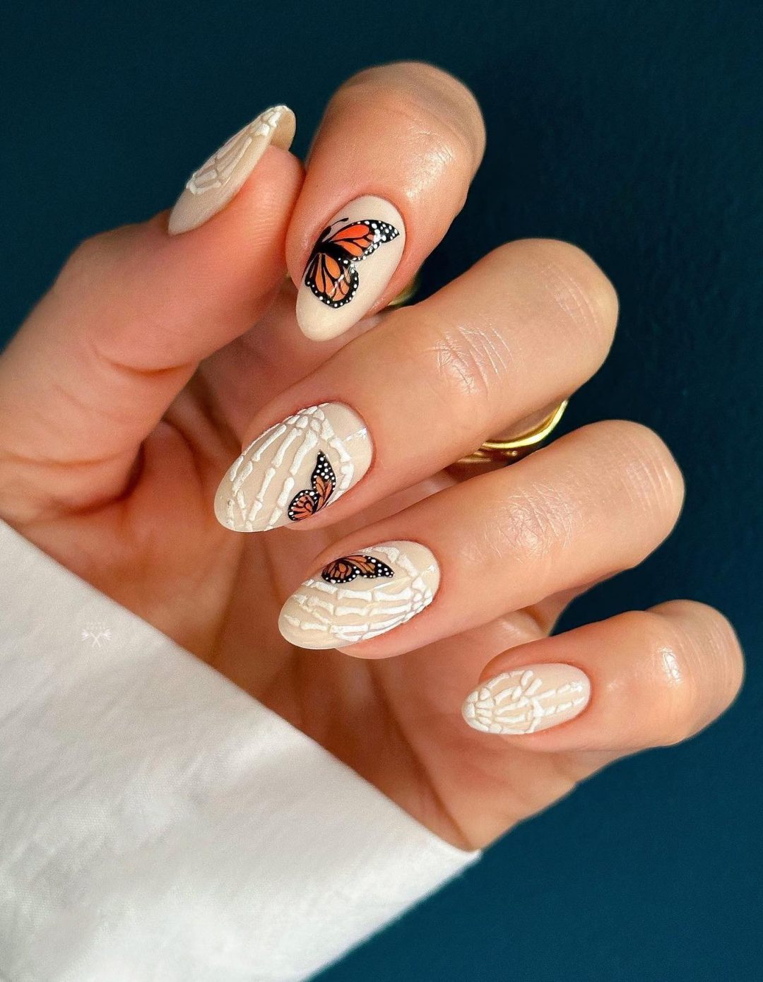 Chic neutral Halloween nails with bones and butterflies.