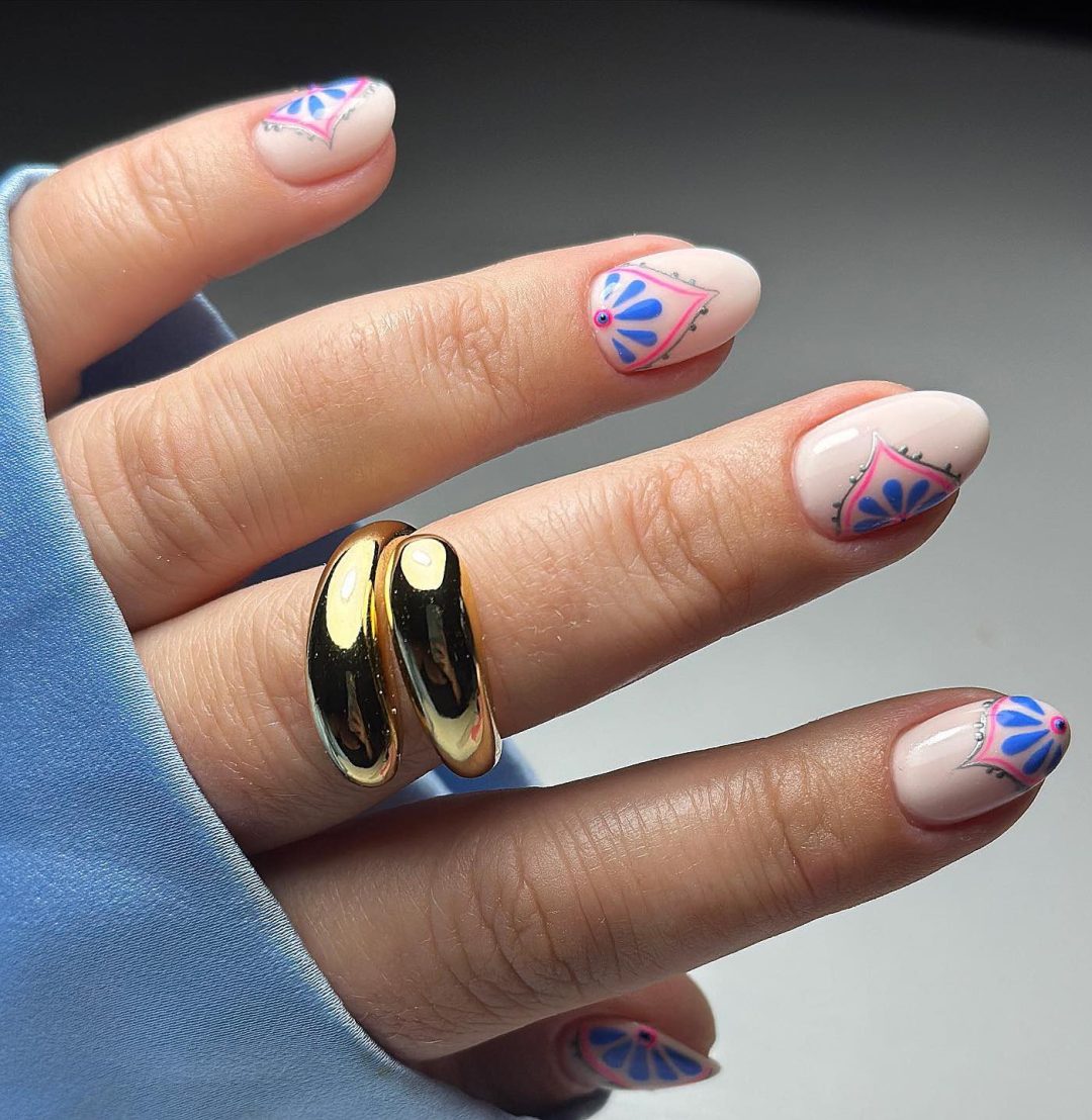 Unhas curtas naturais com desenho de flores rosa e azul.