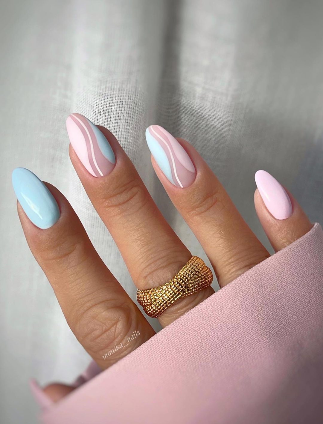 Unhas rosa pastel e azuis com redemoinhos.