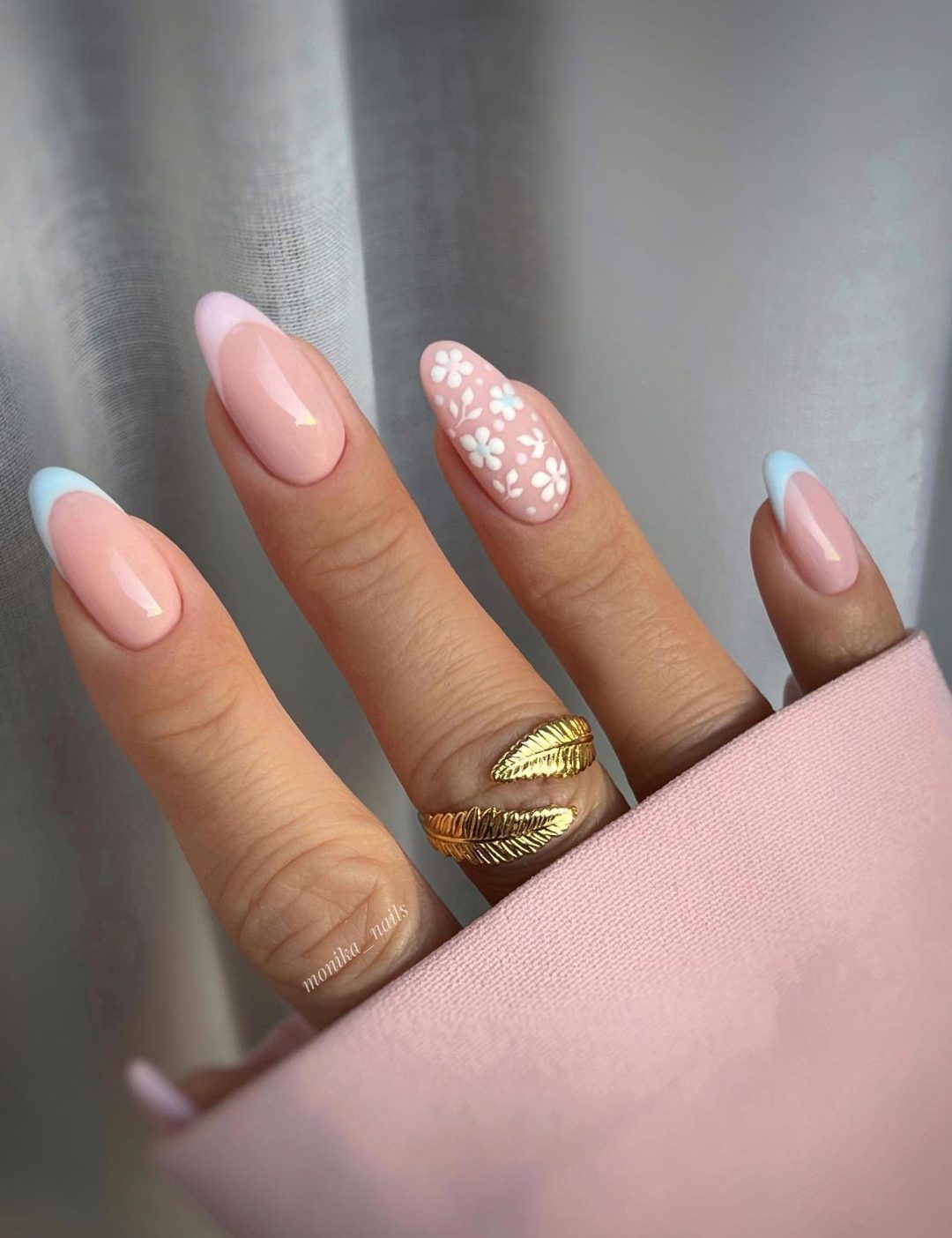 Pastel pink and blue French tip nails with flower nail art.