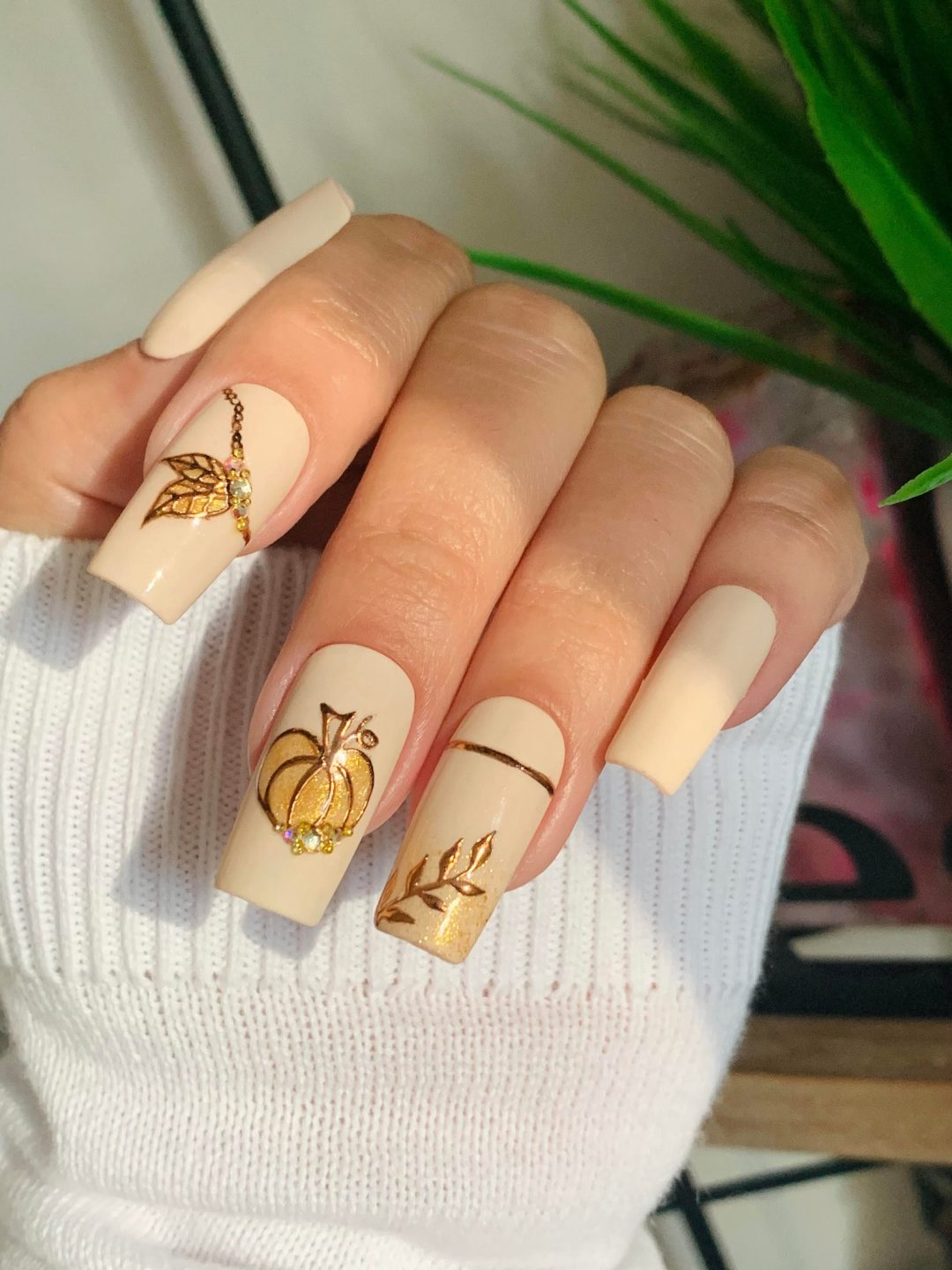 Cute neutral coffin fall nails with golden pumpkins.