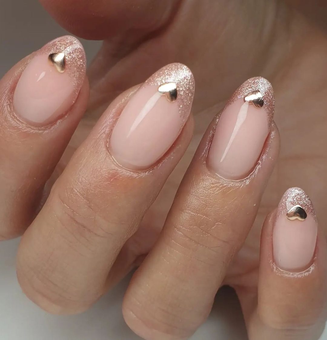 Rose gold French tip nails with hearts.