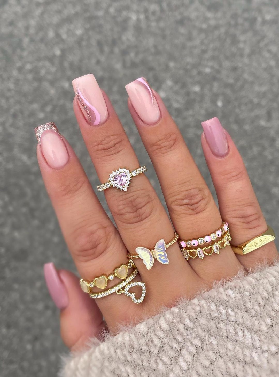 Pink and rose gold French tip nails with swirls.