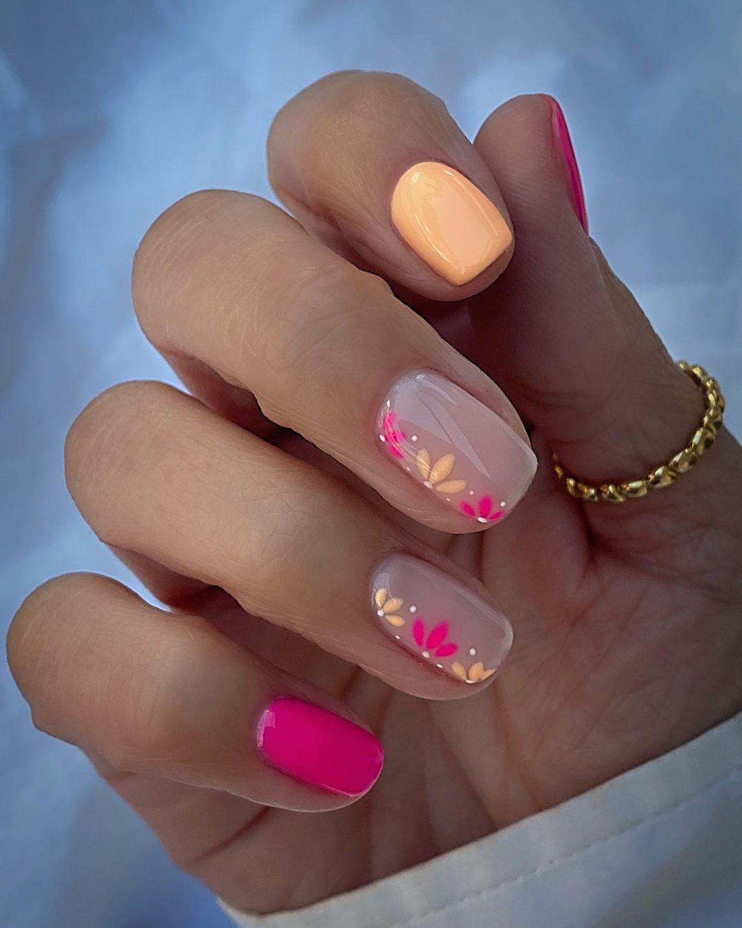 Hot pink and pale orange summer nails with flowers.