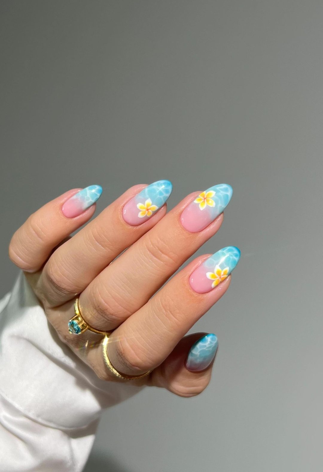 Blue ocean nails for summer with a yellow flower.